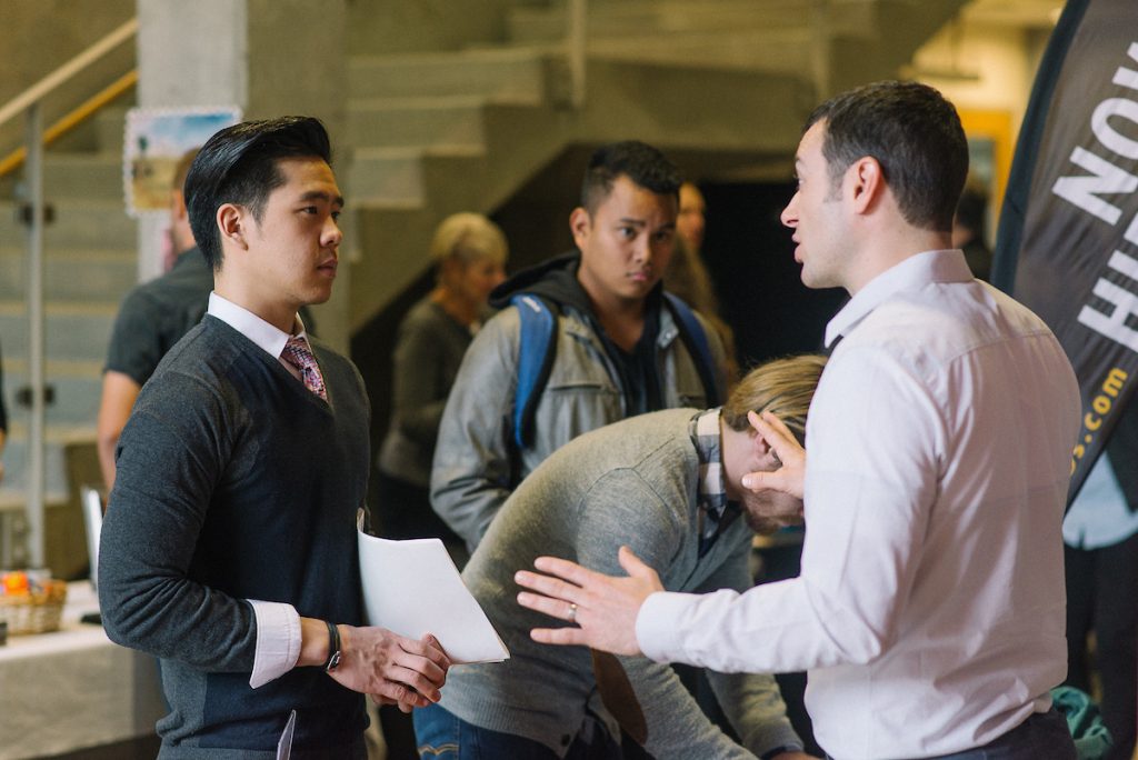 2015 NU Career Fair in HSC. A recruiter with UPS is talking to a student holding their resume.